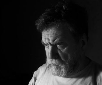 Angry mature bearded man against black background