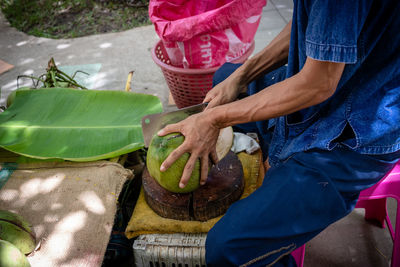 Midsection of man cutting coconut