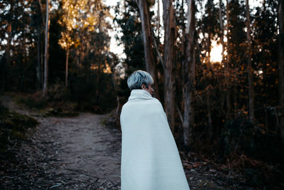 Rear view of man on tree trunk in forest