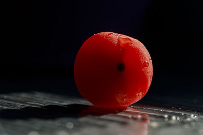 Close-up of wet glass on table against black background