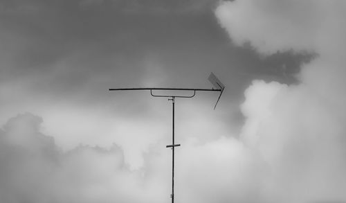 Low angle view of bird on pole against sky