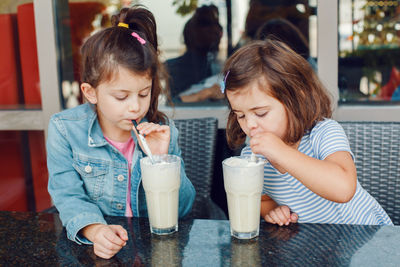 Sisters drinking milk in cafe