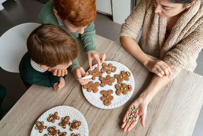 High angle view of mother with kids preparing cookies at home