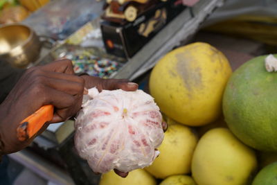 Close-up of hand holding pomelo for sale at market