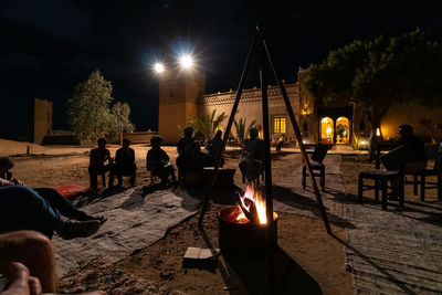 People sitting by campfire at night