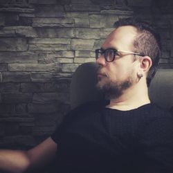 Portrait of young man looking away against wall
