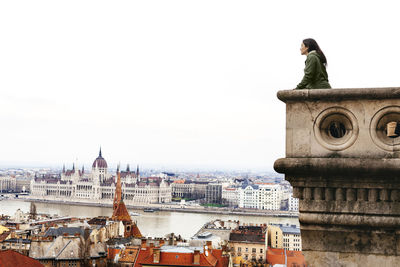 Hungary, budapest, woman looking on the parliament building from castle hill