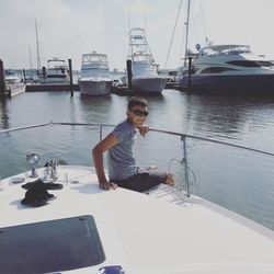 Woman sitting on sailboat against sky