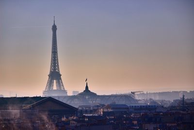 Tower in city against sky during sunset