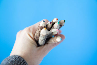 Close-up of hand holding blue over white background