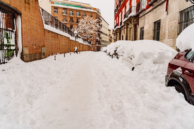 Snow covered street amidst buildings in city