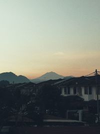 Houses and buildings against clear sky at sunset