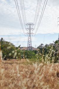 Electricity pylon on field against sky