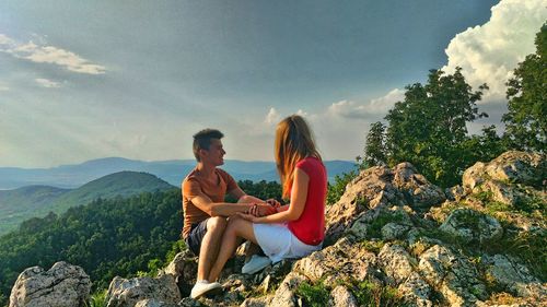 People sitting on mountain against sky