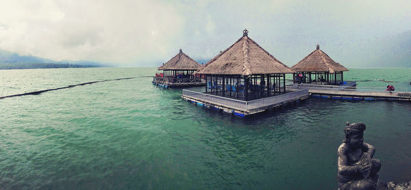 Pier on sea against cloudy sky