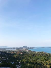 Aerial view of townscape by sea against blue sky