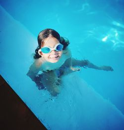 My little girl is enjoying sun-lit swimming pool in blue, pool color matching goggles. 