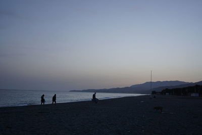 Silhouette people on beach against sky during sunset