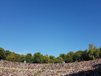 Crowd on field against clear blue sky