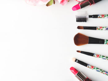 Close-up of make-up brushes with lipsticks on white background