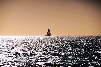 Silhouette of sailboat sailing on sea against clear sky