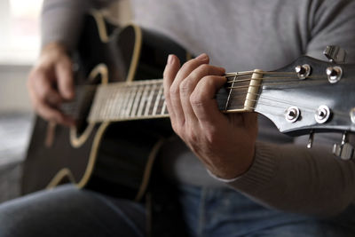 Midsection of man playing guitar