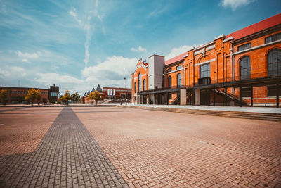 Empty street amidst buildings in city against sky