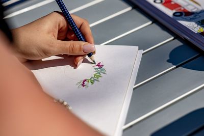 Cropped hand of woman drawing over paper on table