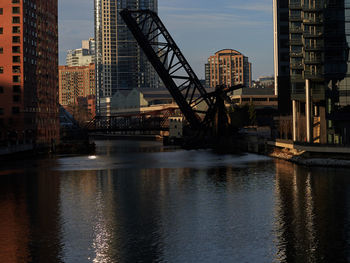Bridge over river by buildings against sky in city
