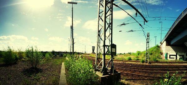 Railroad tracks on field against cloudy sky