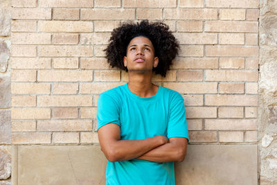 Portrait of young man standing against brick wall