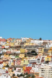 Buildings in city against clear blue sky