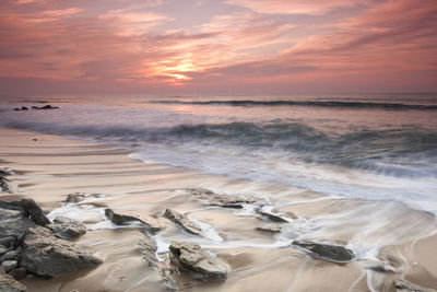 Scenic view of beach against sky during sunset