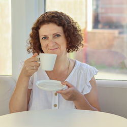 Portrait of young woman using mobile phone while sitting in bathroom