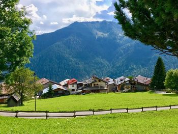 Houses and trees by mountains against sky