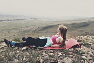 Woman lying down on land against sky