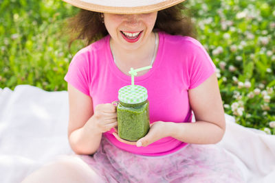 Midsection of woman holding pink while sitting outdoors