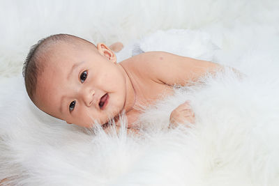 Portrait of cute baby girl lying on bed