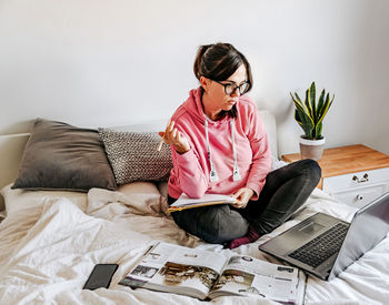 Man using mobile phone while sitting on bed at home