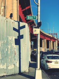 Arrow sign on road in city against sky