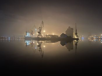Commercial dock by sea against sky at night