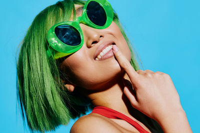 Portrait of woman wearing sunglasses against blue background