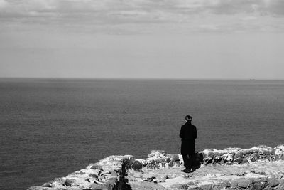 Rear view of man standing by sea against sky