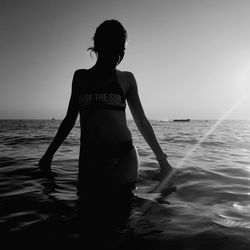 Woman standing at beach against sky