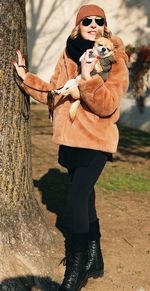 Low section of man standing by tree trunk