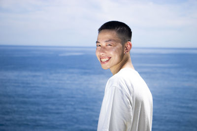 Portrait of smiling man standing in sea against sky