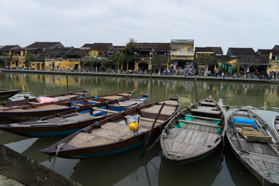 Boats moored in harbor by lake against sky