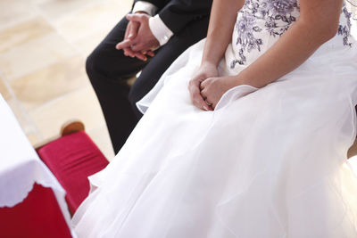 Midsection of bride holding wedding dress