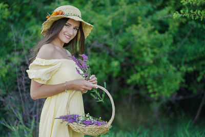 Young woman wearing hat standing against plants