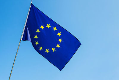 Low angle view of flag against clear blue sky